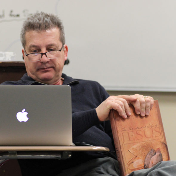 Sacred studies teacher and chaplain Dan Bergstrom holds a copy of the Bible during one of his sophomore Life and Teachings of Christ classes. Photo by Hailee Gilliand. 