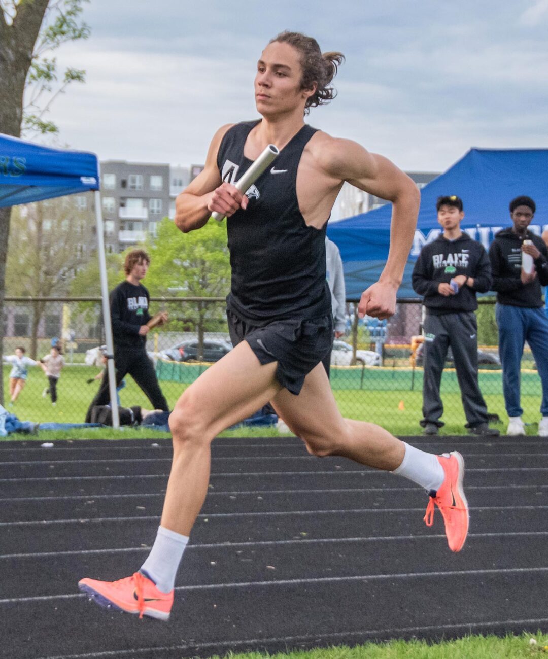 Junior Makai Bates runs a relay leg at Blake. He had the team’s best times in the 400 and 1600 this year. Photo by Ezra Victor.